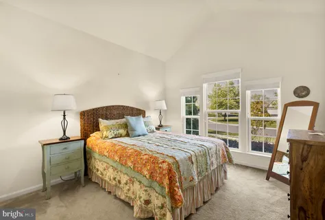 a bedroom with a bed a table and large window