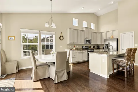 a kitchen with stainless steel appliances granite countertop a dining table chairs refrigerator and cabinets