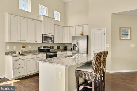 a kitchen with stainless steel appliances granite countertop a stove a refrigerator a white table and chairs