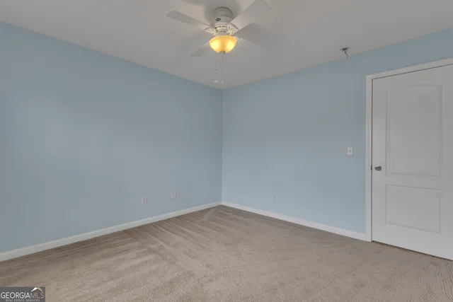 a view of an empty room with wooden floor and stairs