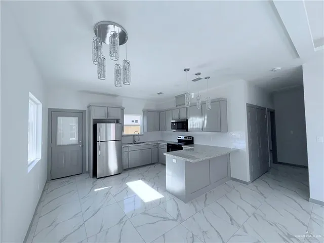 a kitchen with stainless steel appliances granite countertop a sink and stove top oven with white cabinets