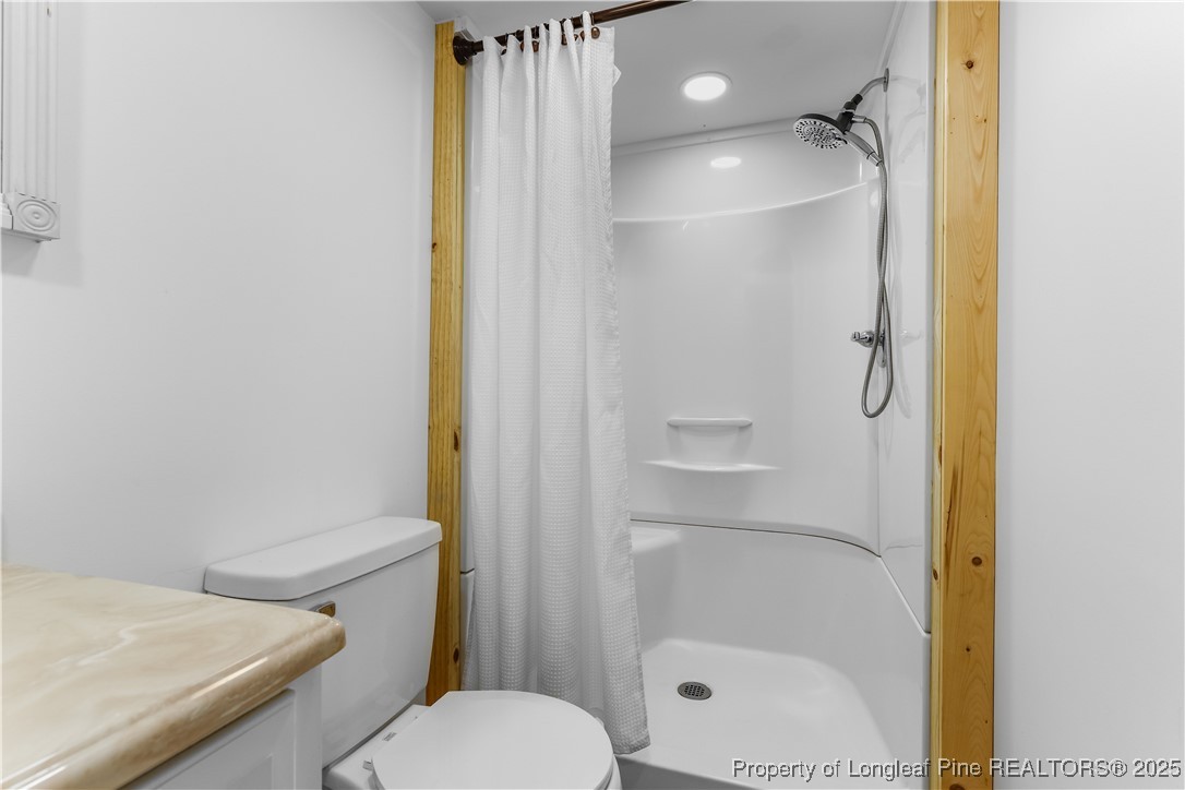 1855 Beaman Woods Road Clinton, NC 28328 - Photo 27 of 50 a bathroom with a granite countertop toilet and a shower