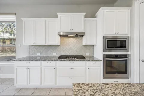 a kitchen with granite countertop white cabinets and stainless steel appliances