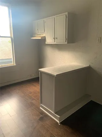 an empty room with wooden floor and cabinet