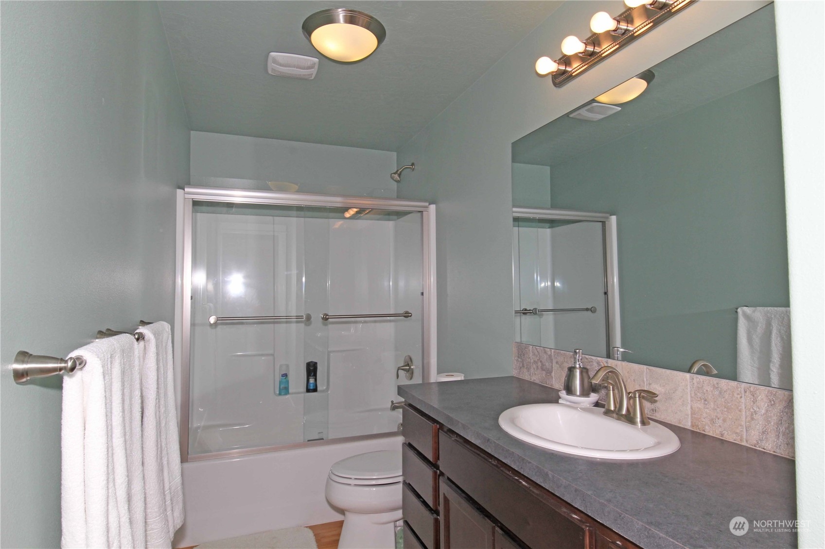 1004 Riverside Avenue Twisp, WA 98856 - Photo 17 of 40 a bathroom with a granite countertop sink a toilet a mirror and shower