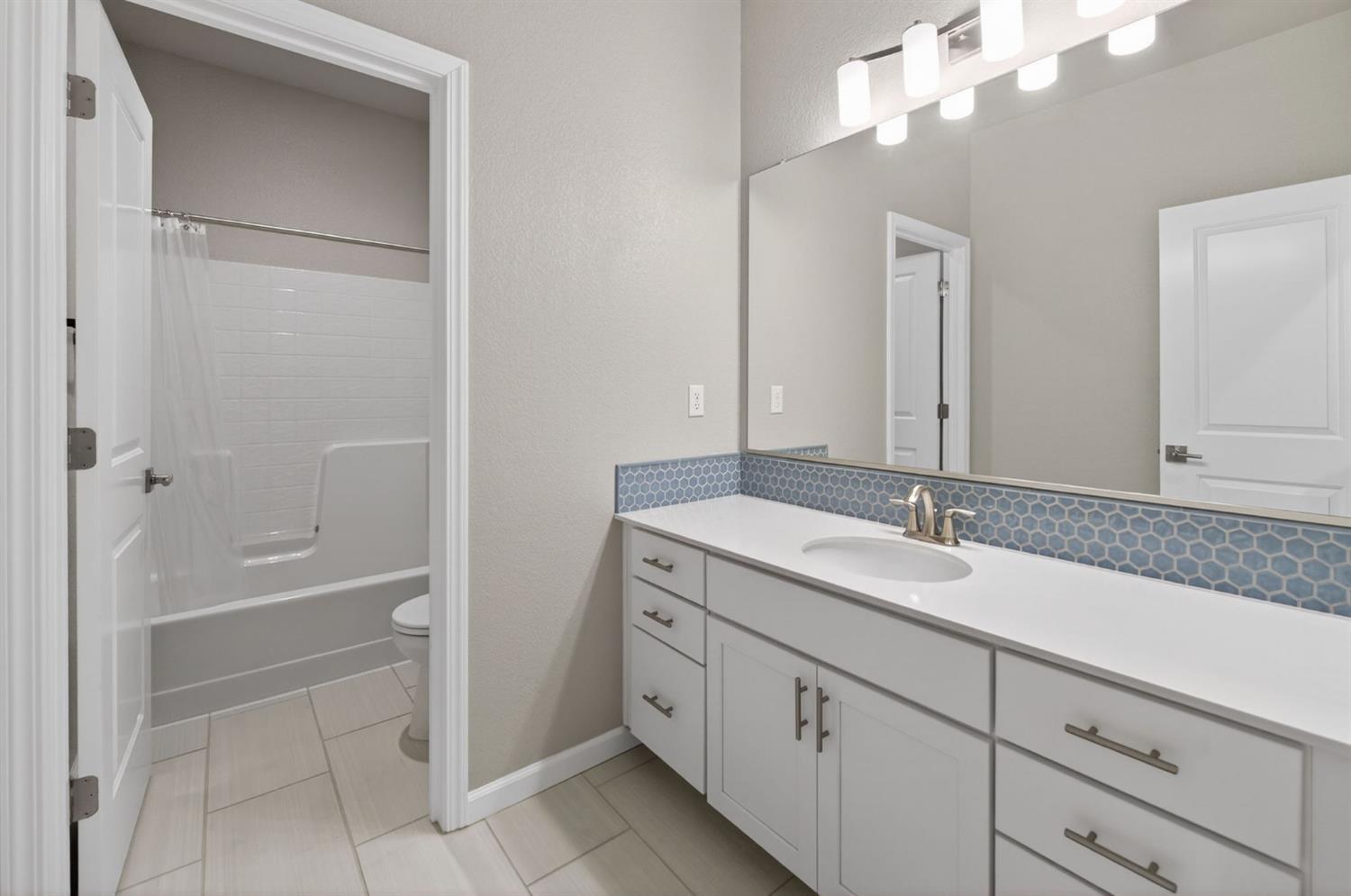 2431 Creekview Drive Merced, CA 95340 - Photo 27 of 38 a bathroom with a granite countertop sink a mirror and a bathtub