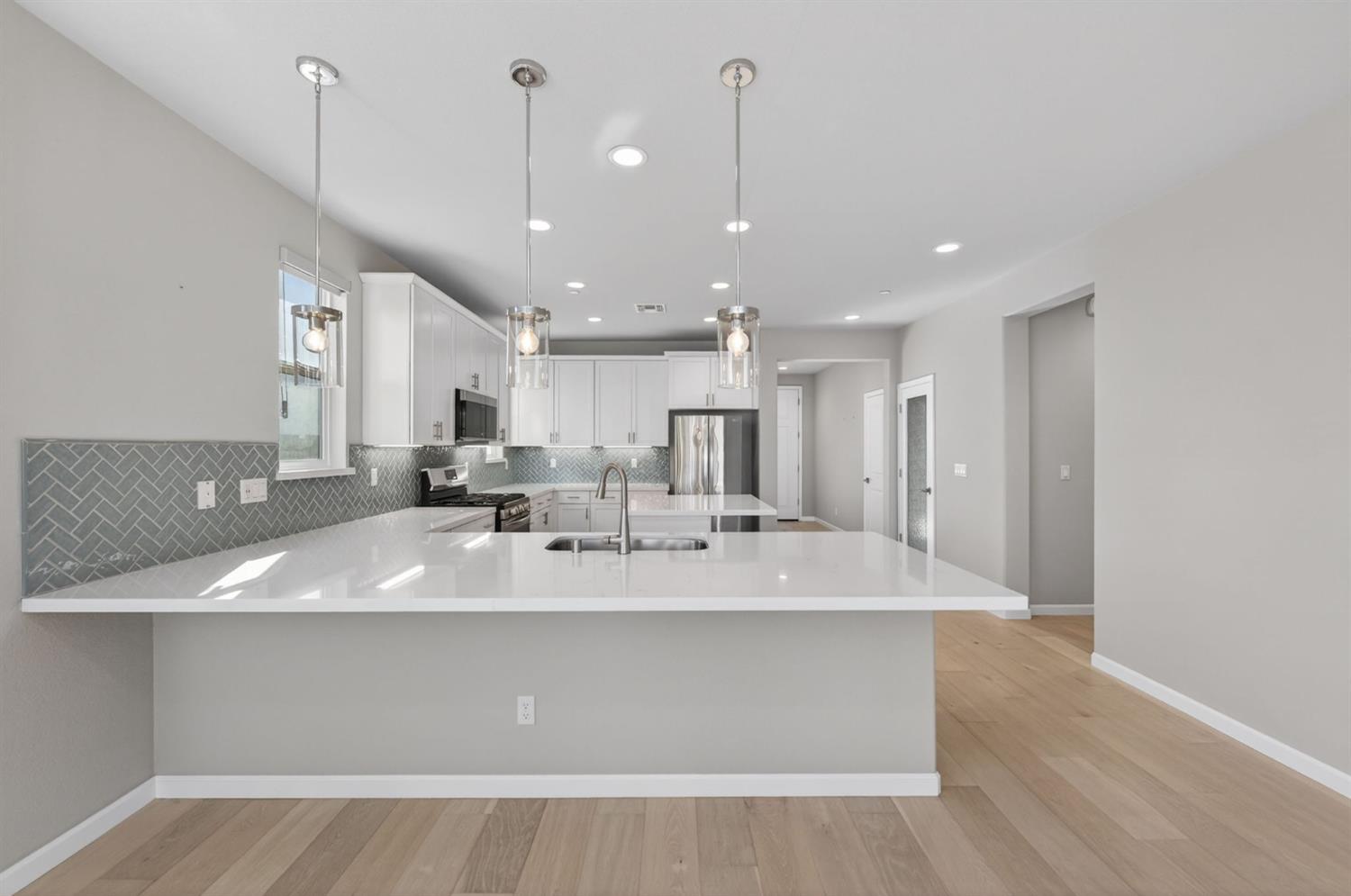 2431 Creekview Drive Merced, CA 95340 - Photo 7 of 38 a large white kitchen with a large island oven a sink with stainless steel appliances