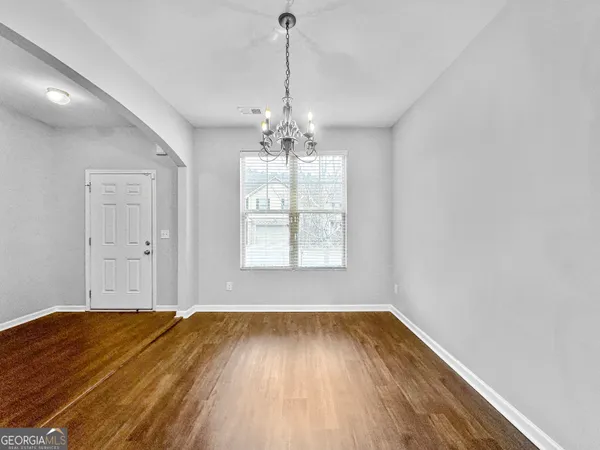a view of a room with wooden floor exposed radiator and a window