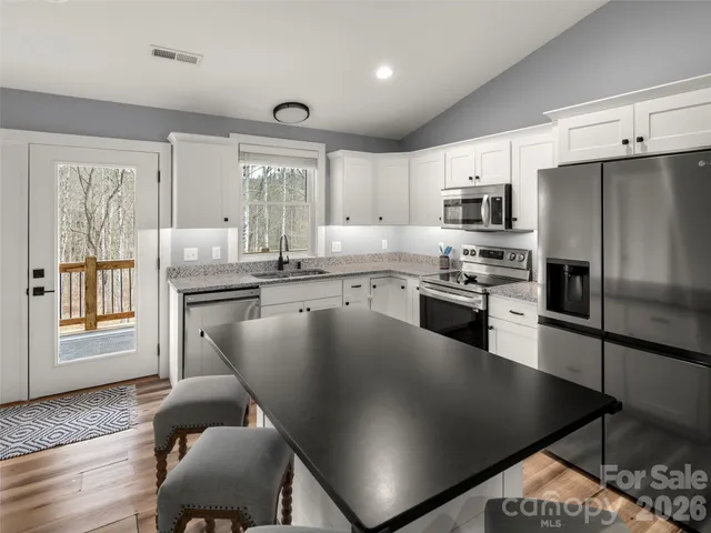 a kitchen with stainless steel appliances granite countertop a stove a sink a microwave and a refrigerator