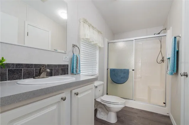 a bathroom with a granite countertop sink a toilet and shower