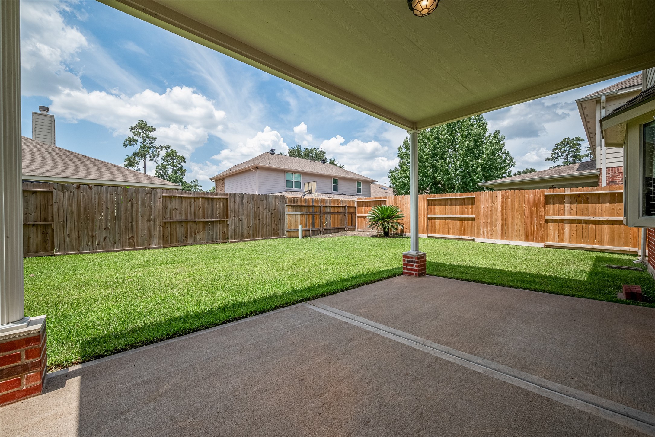 9218 Memorial Pines Way Spring, TX 77379 - Photo 38 of 39 Aa spacious backyard with a covered patio, perfect for relaxation or entertaining. The wooden fence is in perfect condition, offering privacy for the well-maintained lawn. Ideal for outdoor activities and gatherings.