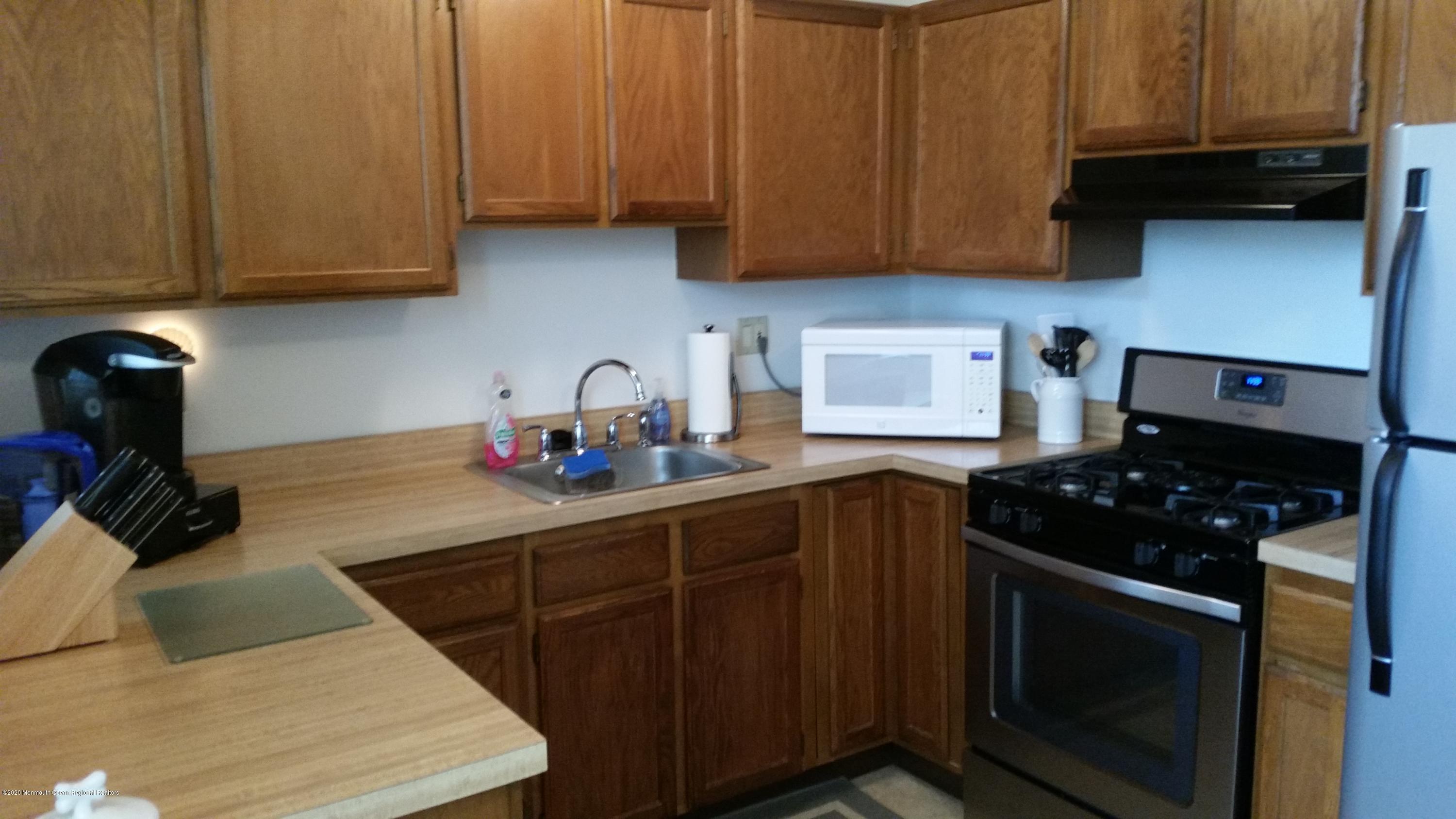 14 Carol Court Tinton Falls, NJ 07724 - Photo 3 of 13 a kitchen with stainless steel appliances a stove a sink dishwasher and cabinets with wooden floor