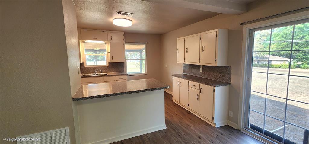 2016 Gavin Road Tool, TX 75143 - Photo 12 of 26 Kitchen featuring white cabinetry, a central island with a stone-finish countertop, vinyl flooring, and a sliding glass door