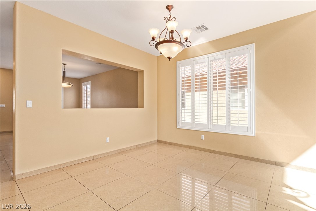 1477 Rancho Ridge Drive Henderson, NV 89012 - Photo 7 of 46 A classic chandelier illuminates the dining area, featuring stylish plantation shutters and tile flooring.