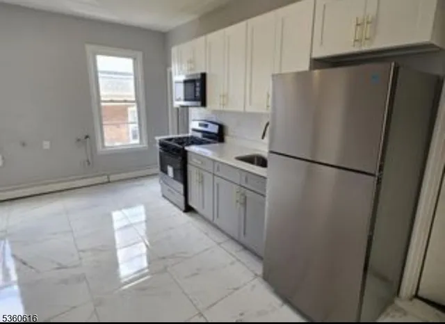 a kitchen with stainless steel appliances a refrigerator a sink a stove a microwave and cabinets