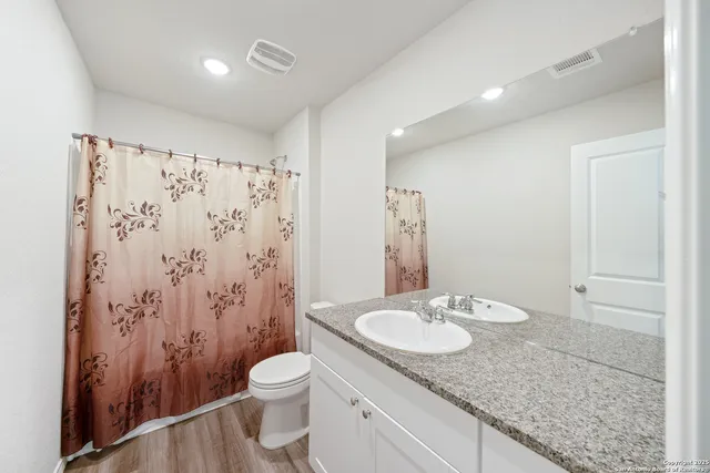 a bathroom with a granite countertop sink toilet and shower