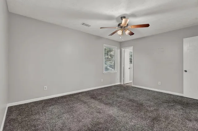 an empty room with windows and fan