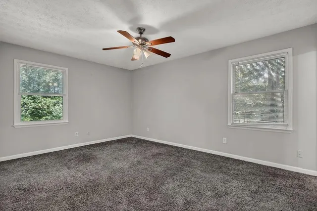 a view of an empty room with chandelier fan and wooden floor