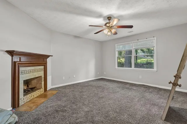 a view of an empty room with window and chandelier fan