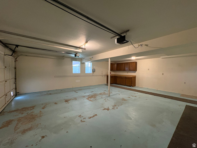 595 Meadowlark Road Orem, UT 84097 - Photo 64 of 87 Spacious garage featuring an automatic overhead door, built-in cabinetry with counter space, two windows for natural light, and ceiling-mounted fluorescent lighting