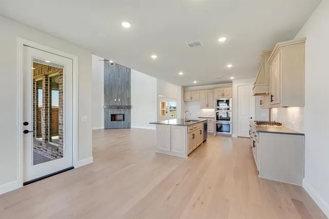 a view of kitchen with kitchen island wooden floor center island and stainless steel appliances