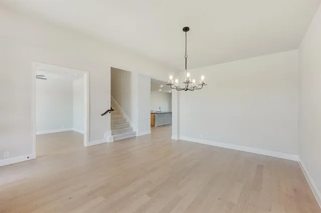 a view of an empty room with wooden floor and a chandelier