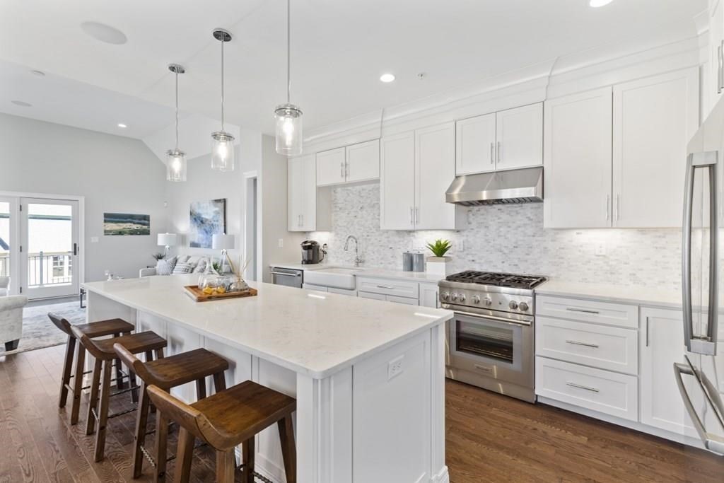 a kitchen with stainless steel appliances a stove a table a sink refrigerator and cabinets