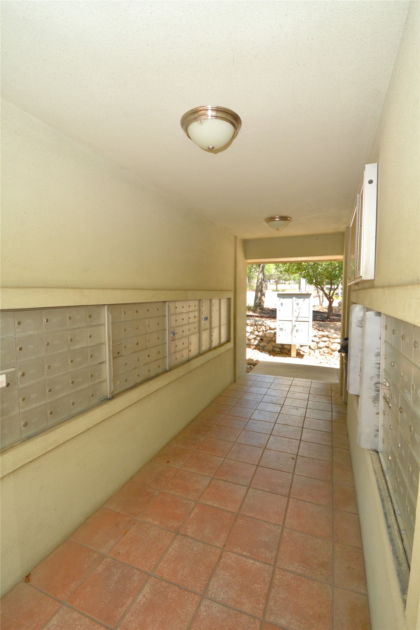 7701 Rialto Boulevard, Unit 124 Austin, TX 78735 - Photo 18 of 23 Covered outdoor corridor featuring terra cotta tile flooring, flush mount ceiling lights, and multiple banks of private mailboxes