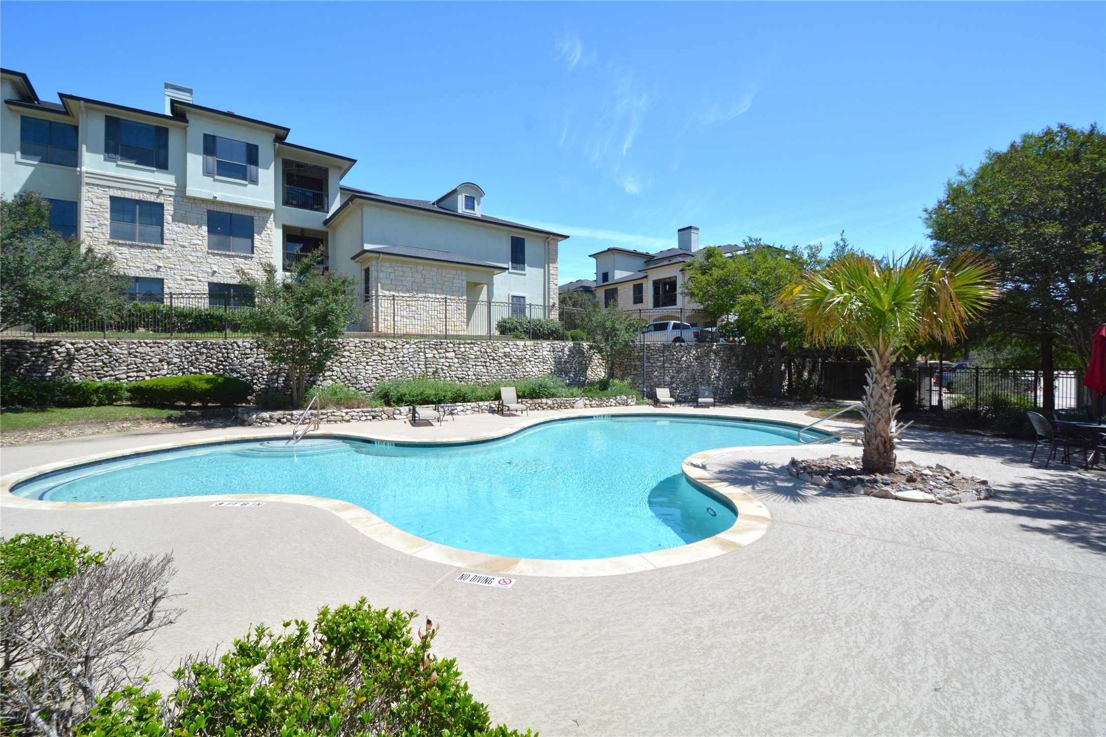 7701 Rialto Boulevard, Unit 124 Austin, TX 78735 - Photo 23 of 23 Resort-style pool area featuring a freeform swimming pool with integrated steps, surrounded by a textured concrete deck