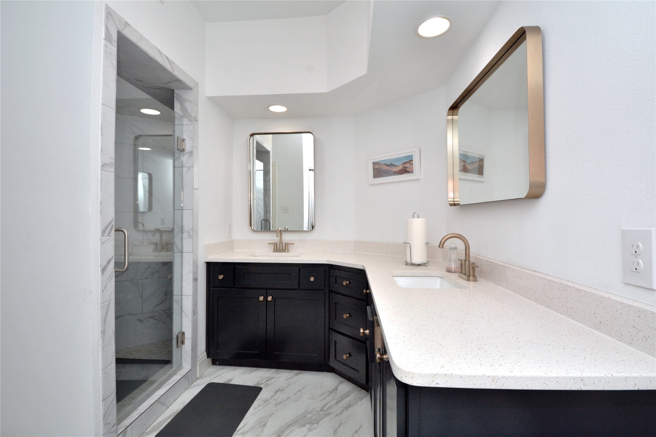 7701 Rialto Boulevard, Unit 124 Austin, TX 78735 - Photo 9 of 23 Bathroom featuring a glass-enclosed shower with marble-look tile, a dual-sink vanity with dark cabinetry, white speckled countertops, and brushed nickel fixtures