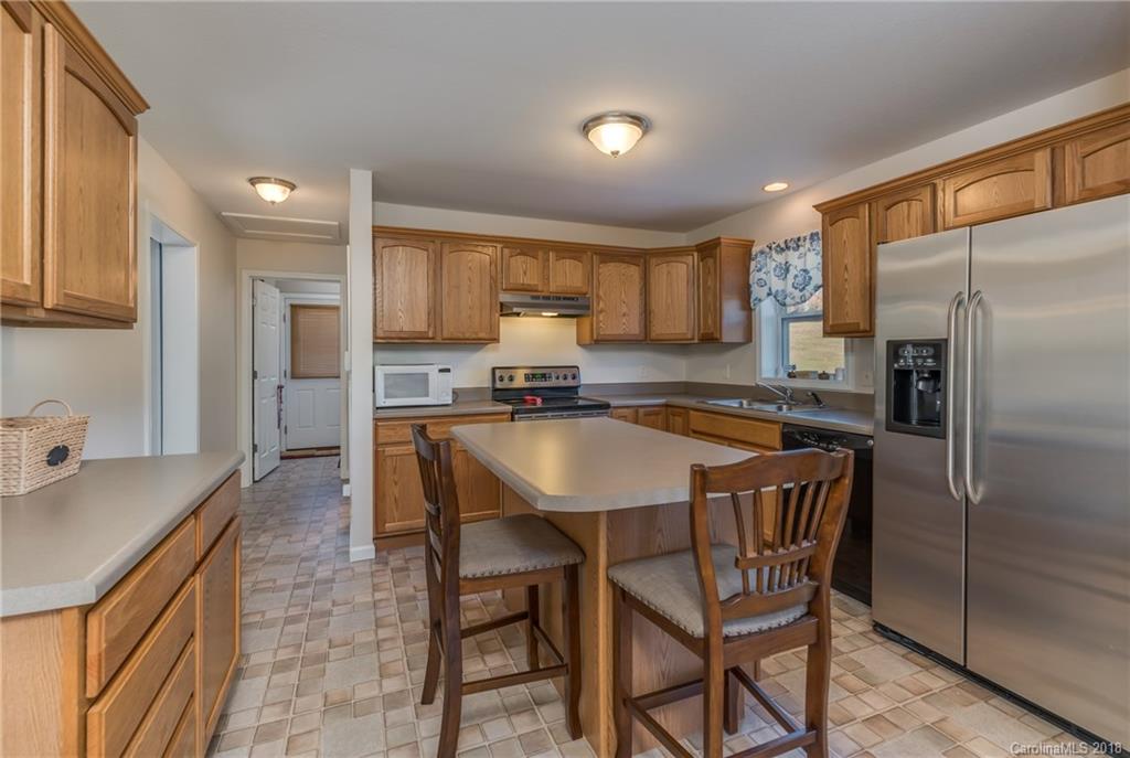1632 Maple Creek Road Rutherfordton, NC 28139 - Photo 9 of 20 a kitchen with stainless steel appliances granite countertop a refrigerator a sink a stove a dining table and chairs