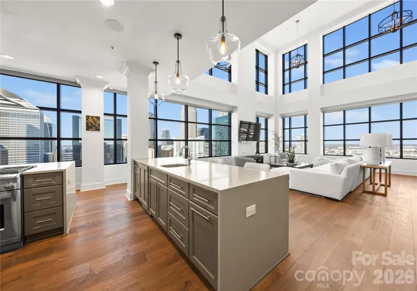 a large living room with stainless steel appliances kitchen island granite countertop a large kitchen island a stove a chimney a sink and cabinets