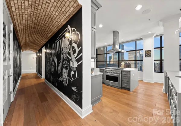 a kitchen with stainless steel appliances kitchen island granite countertop a refrigerator a stove and a wooden floors