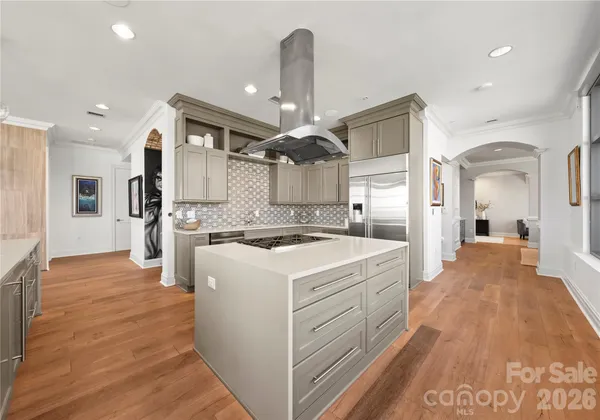 a large kitchen with kitchen island a stove a sink dishwasher and a dining table with wooden floor