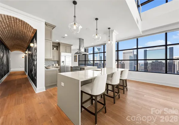 a kitchen with stainless steel appliances kitchen island granite countertop a stove a refrigerator a dining table and chairs with wooden floor