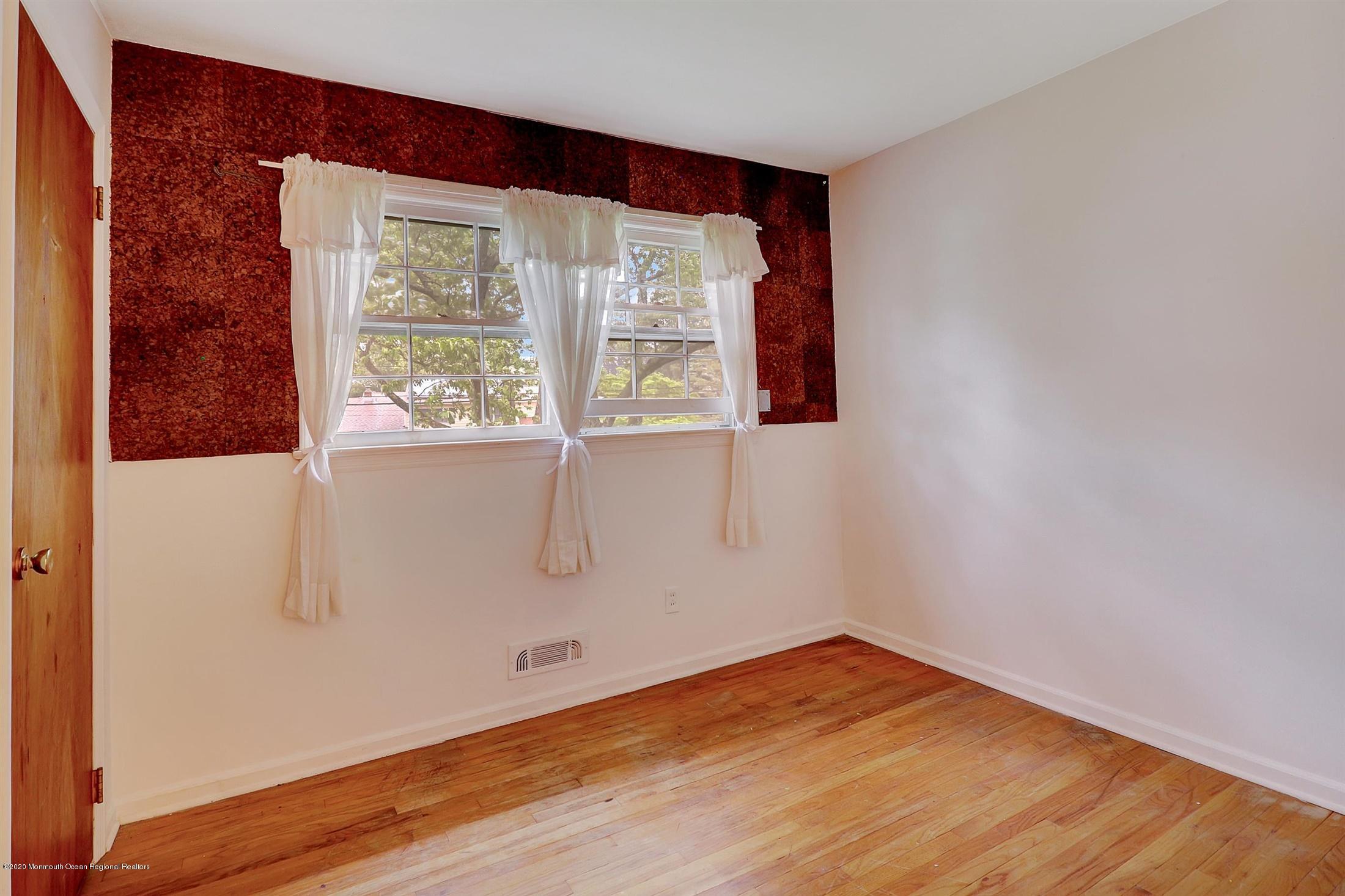 107 Jumping Brook Road Lincroft, NJ 07738 - Photo 20 of 30 a view of an empty room with wooden floor and a window