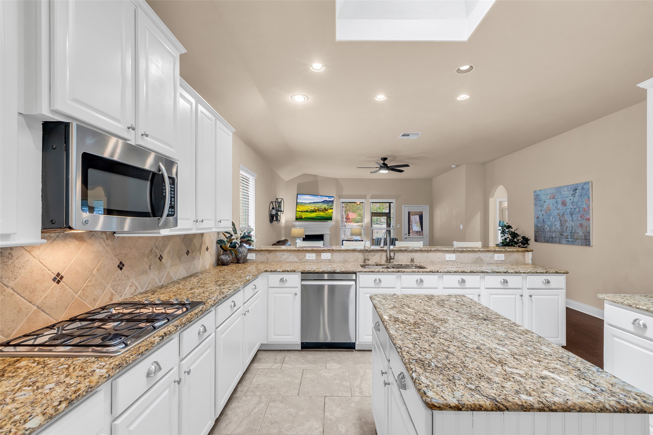 10 Pilot Rock Place Tomball, TX 77375 - Photo 7 of 23 a large kitchen with stainless steel appliances granite countertop a stove top oven a sink dishwasher and white cabinets with wooden floor