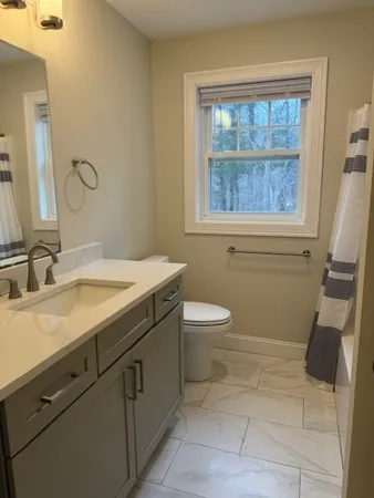 a bathroom with a sink a toilet and a window