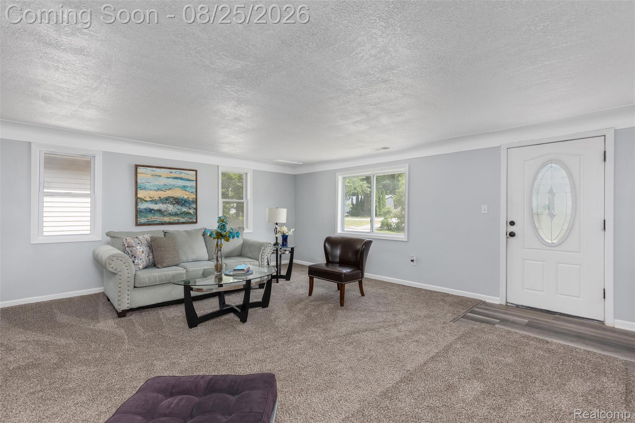 1156 Rinn Street Burton, MI 48509 - Photo 5 of 25 Light gray wall paint, white trim, multiple windows, front entry door with decorative glass, wood-finish flooring at entry