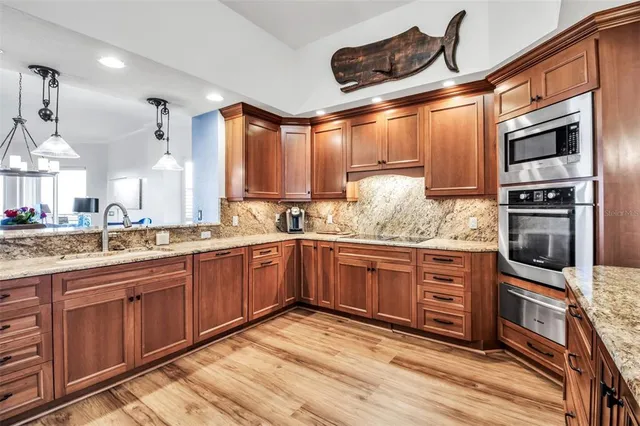 a kitchen with stainless steel appliances granite countertop a sink and wooden cabinets