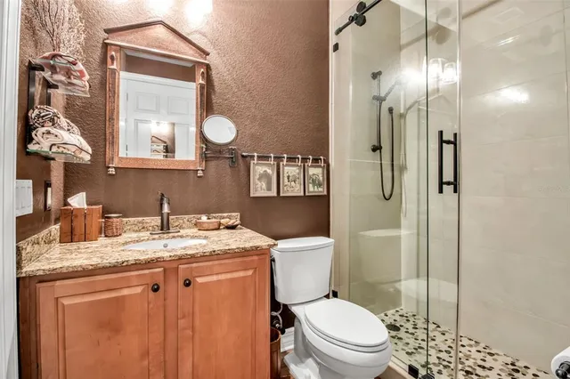 a bathroom with a granite countertop sink toilet a mirror and shower