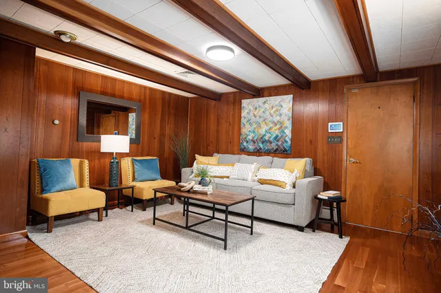 a living room with furniture a rug kitchen view and a large window