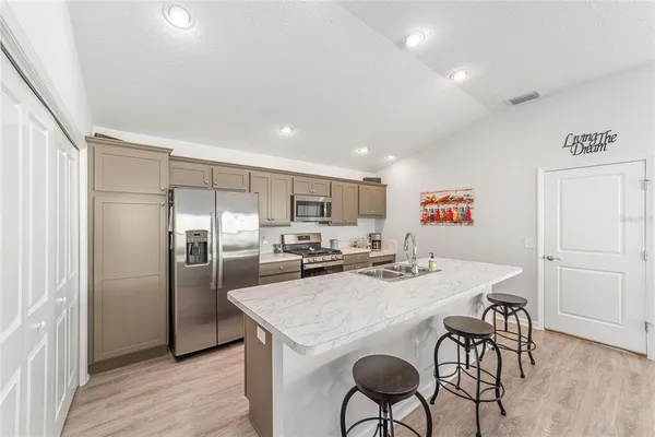 a kitchen with stainless steel appliances granite countertop a dining table chairs refrigerator and cabinets