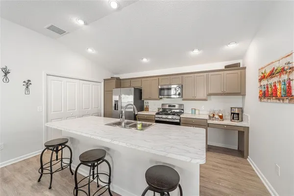 a kitchen with stainless steel appliances a sink a stove a refrigerator cabinets and dining table