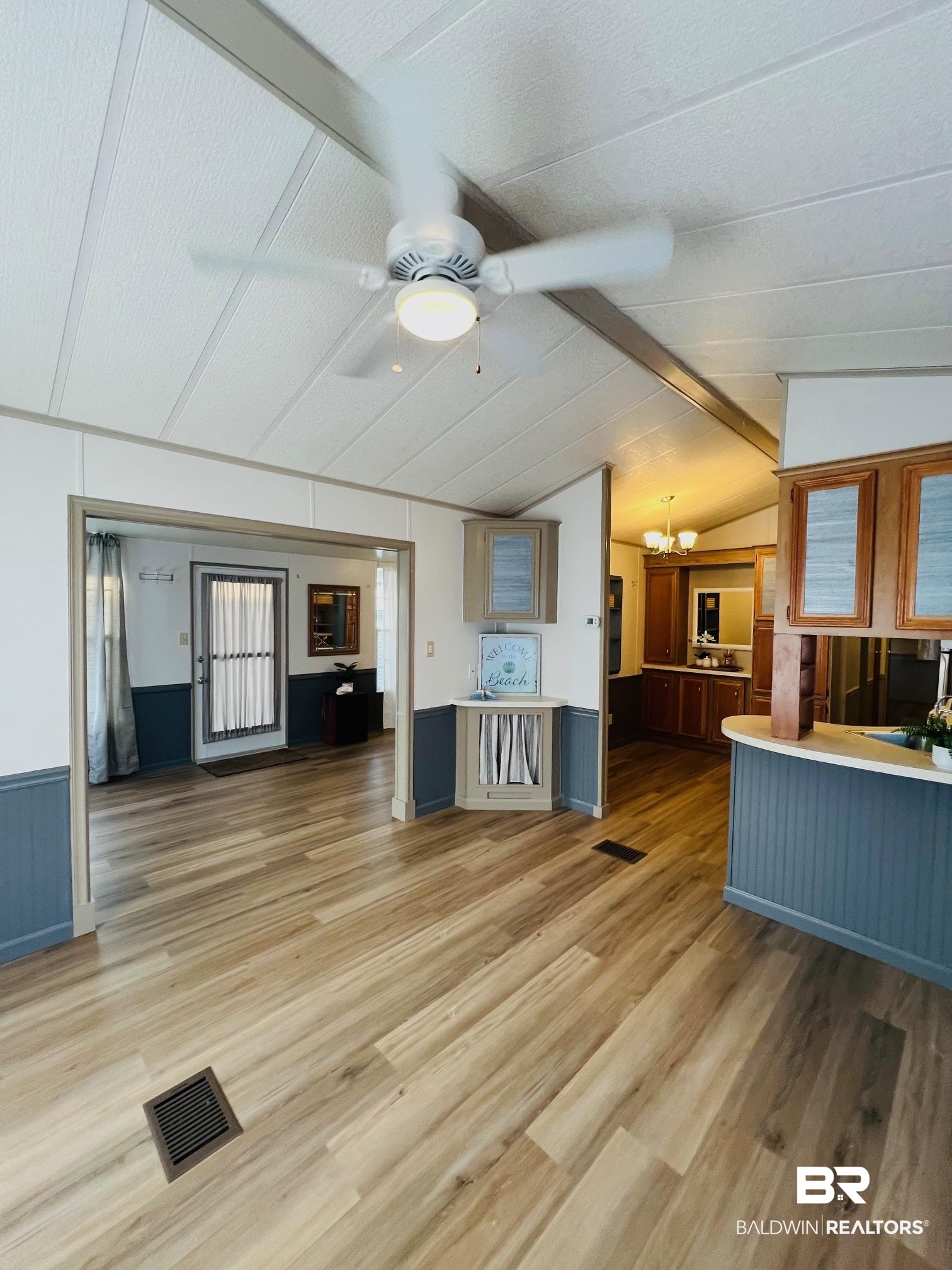 195 Defuniak Loop Lillian, AL 36549 - Photo 5 of 37 Kitchen with lofted ceiling with beams, light wood-style flooring, visible vents, ceiling fan with notable chandelier, and wainscoting