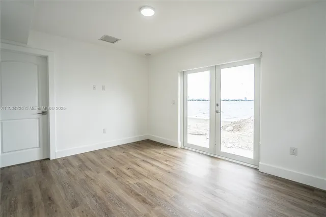 an empty room with wooden floor and window
