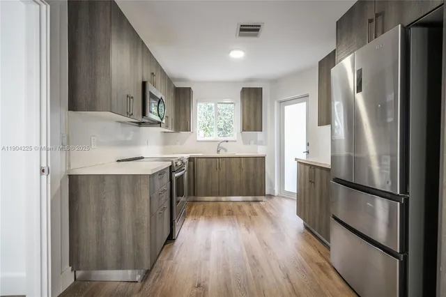 a kitchen with wooden floors and stainless steel appliances