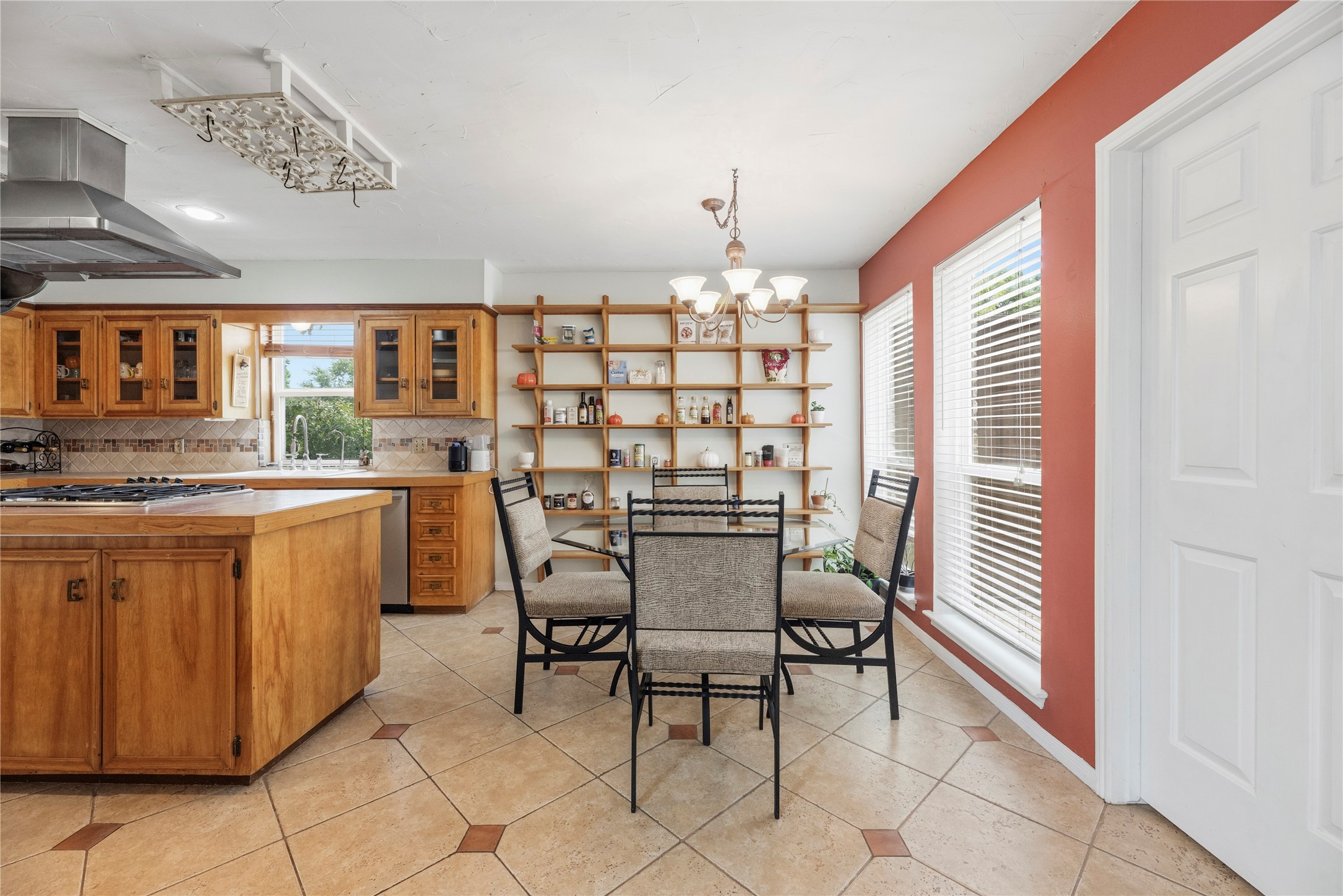 14203 Wickersham Lane Houston, TX 77077 - Photo 6 of 25 Sunny breakfast nook off the kitchen featuring extensive floor-to-ceiling built-in open shelving, large double windows with blinds, and elegant diagonal tile flooring.