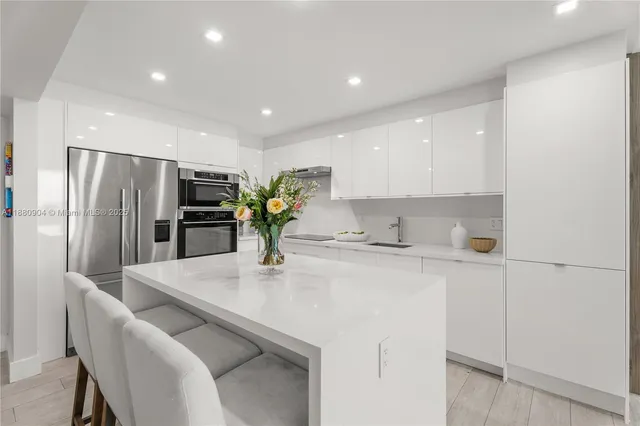 a kitchen with stainless steel appliances a sink a refrigerator and a counter top space