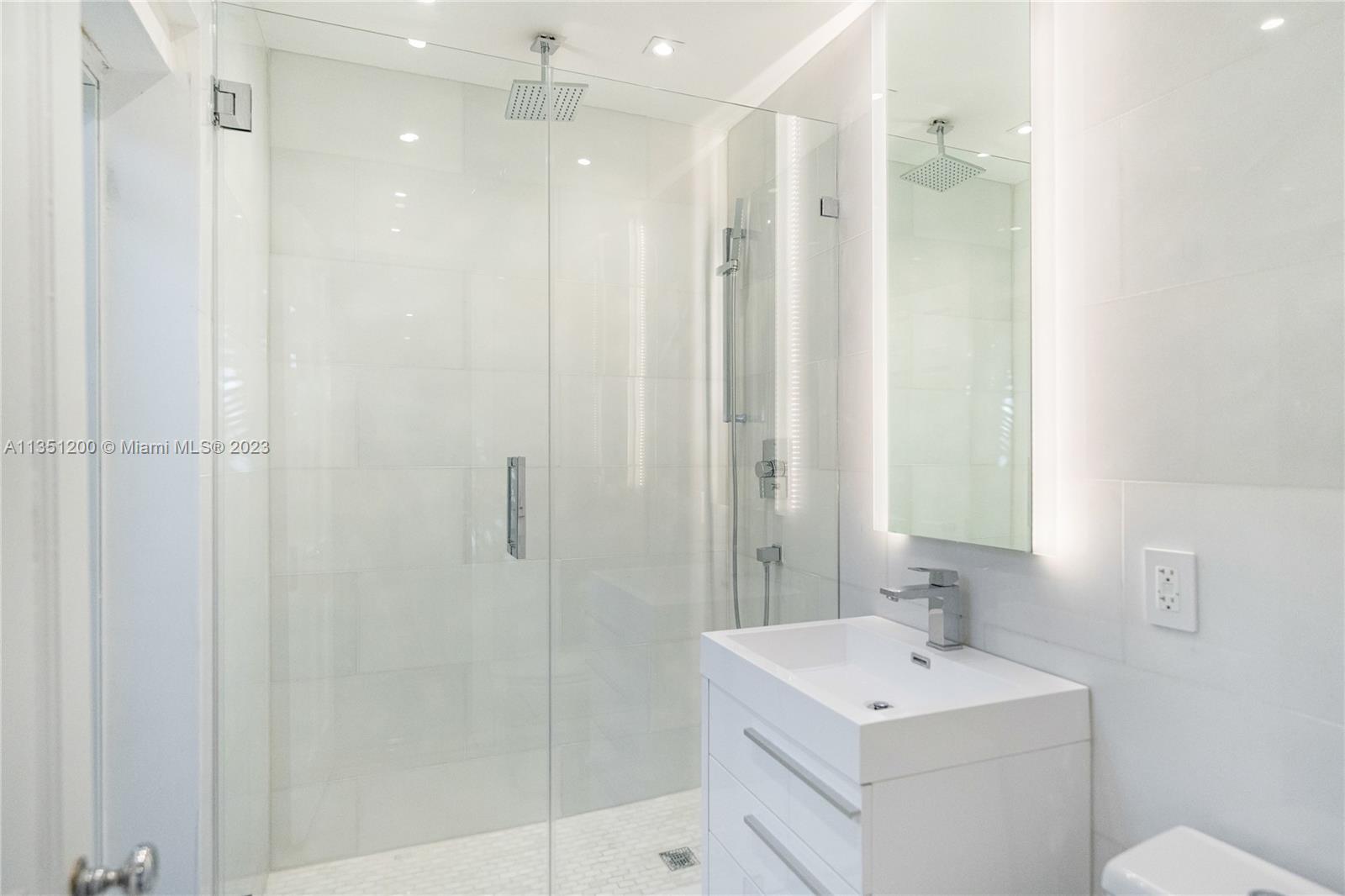 5512 La Gorce Drive Miami Beach, FL 33140 - Photo 26 of 35 a bathroom with a shower a sink and mirror